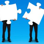 Two businessmen assembling puzzles