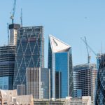 City of London, UK Cityscape of construction cranes on modern architecture skyline of skyscrapers during summer at day and blue sky