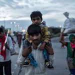 Indian-migrant-worker-carries-his-son-as-they-walk-along-a-road-with-others-to-return-to-their-village-in-New-Delhi_171a1503c89_medium
